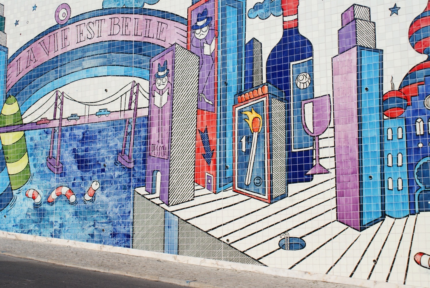 A bridge under a La vie est belle banner, bottles and towers on André Saraiva's tiled Lisbon mural
