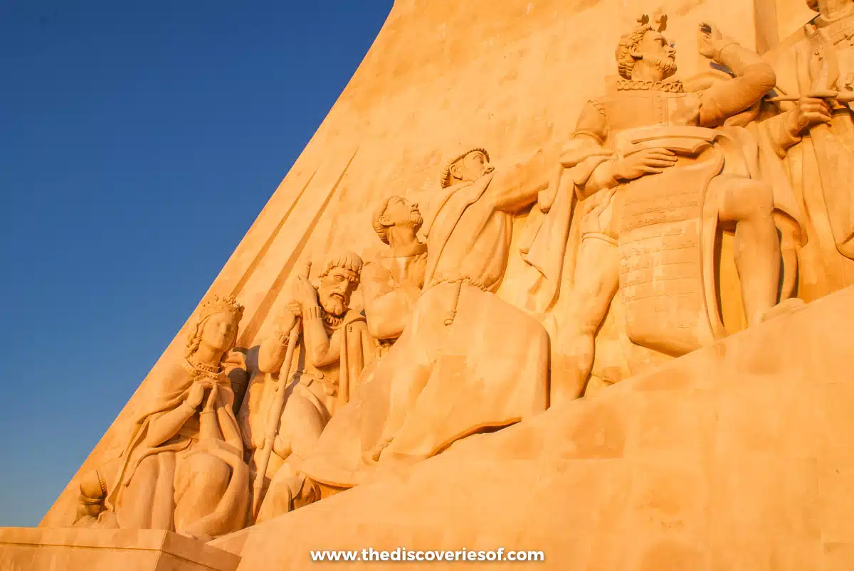 Carved stone explorers lining the side of the Monument to the Discoveries against a blue sky in Belém