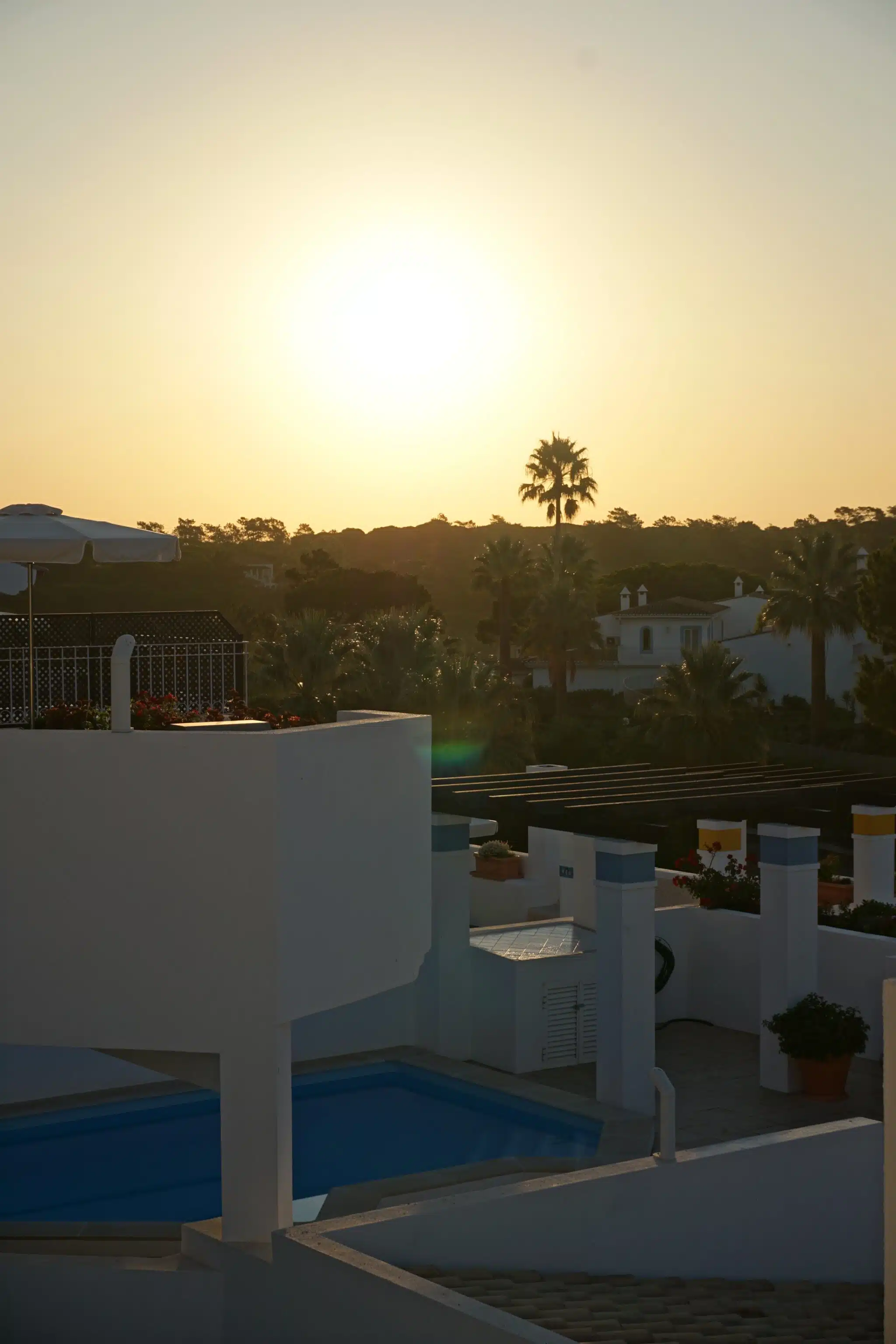The sun rising over palms and villa rooftops seen from a villa terrace at Four Seasons Fairways, Quinta do Lago