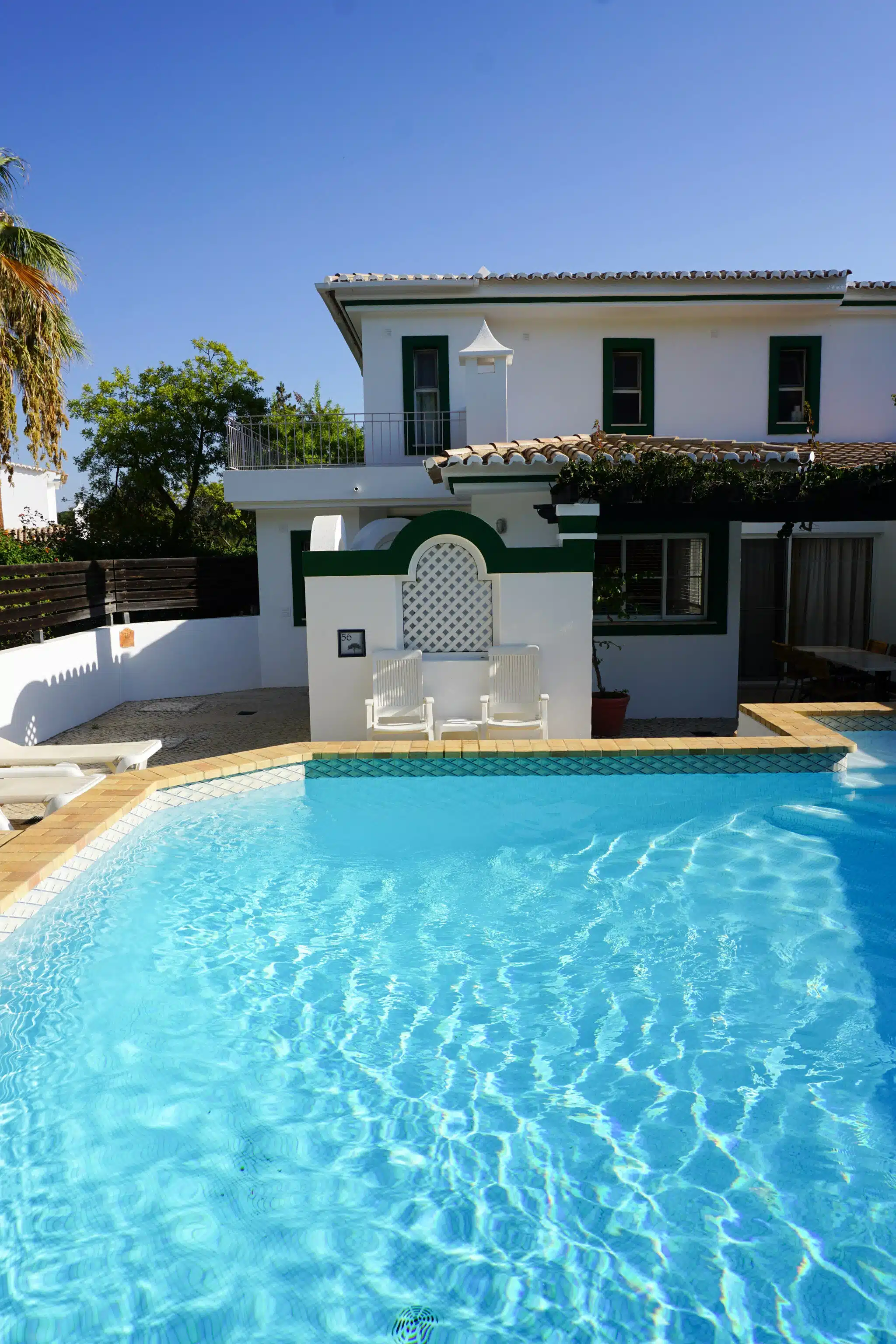 A two-storey whitewashed villa with a green tiled roof and a private swimming pool at Four Seasons Fairways