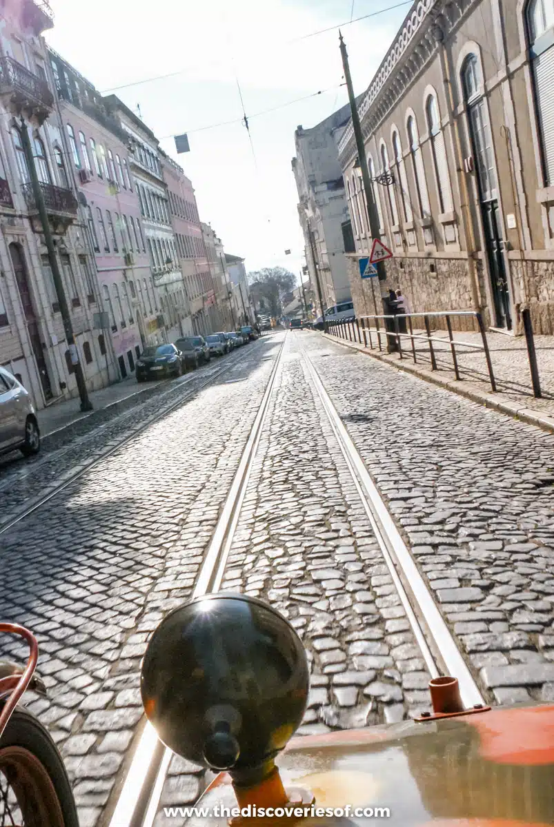 View from a vintage sidecar rolling over cobbles and tram tracks on a Lisbon street