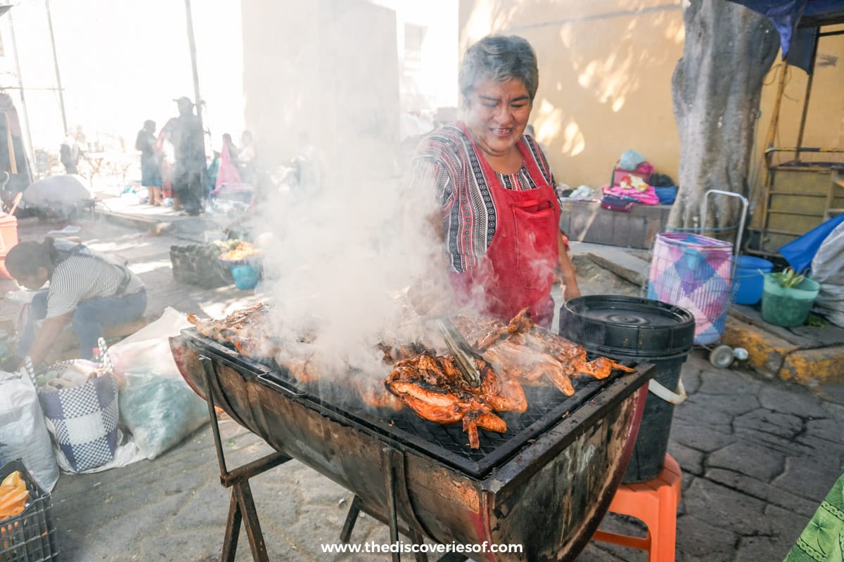 Woman cooking chickens at Tlacaloula