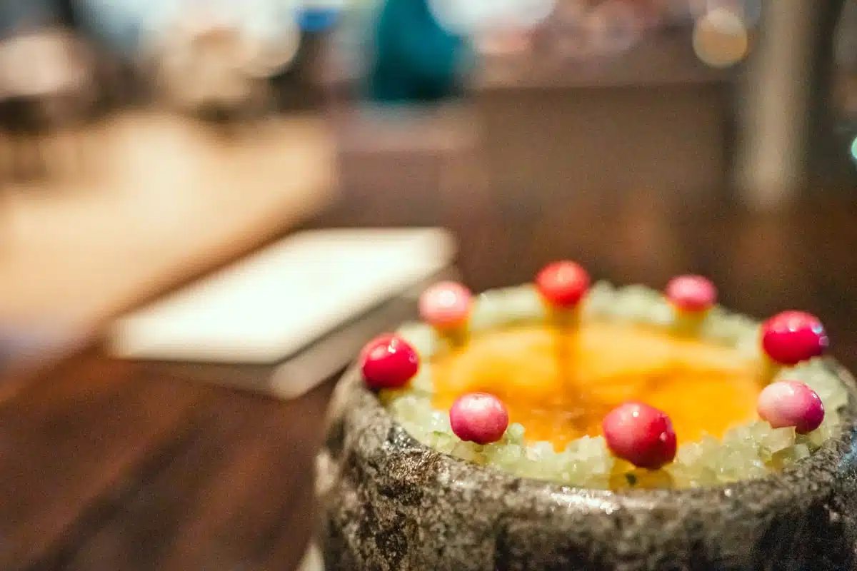 Glazed orange ice brûlée ringed with small red and pink fruit over crushed ice at Boragó