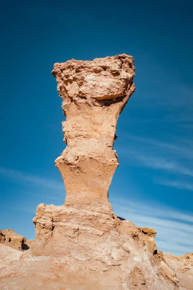Tall wind-eroded rock tower with a wide flat cap against a deep blue sky at Ckamur