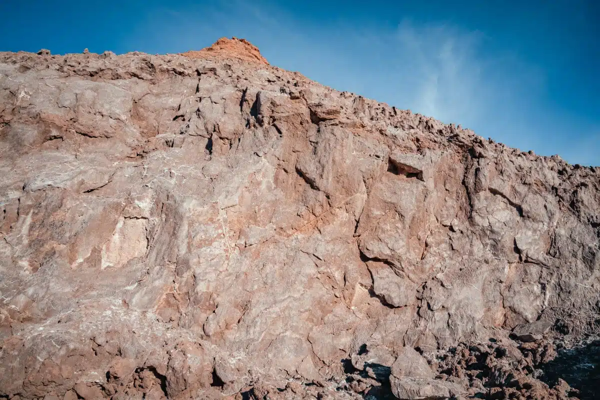 Steep rock face streaked with salt under a blue sky at Ckamur