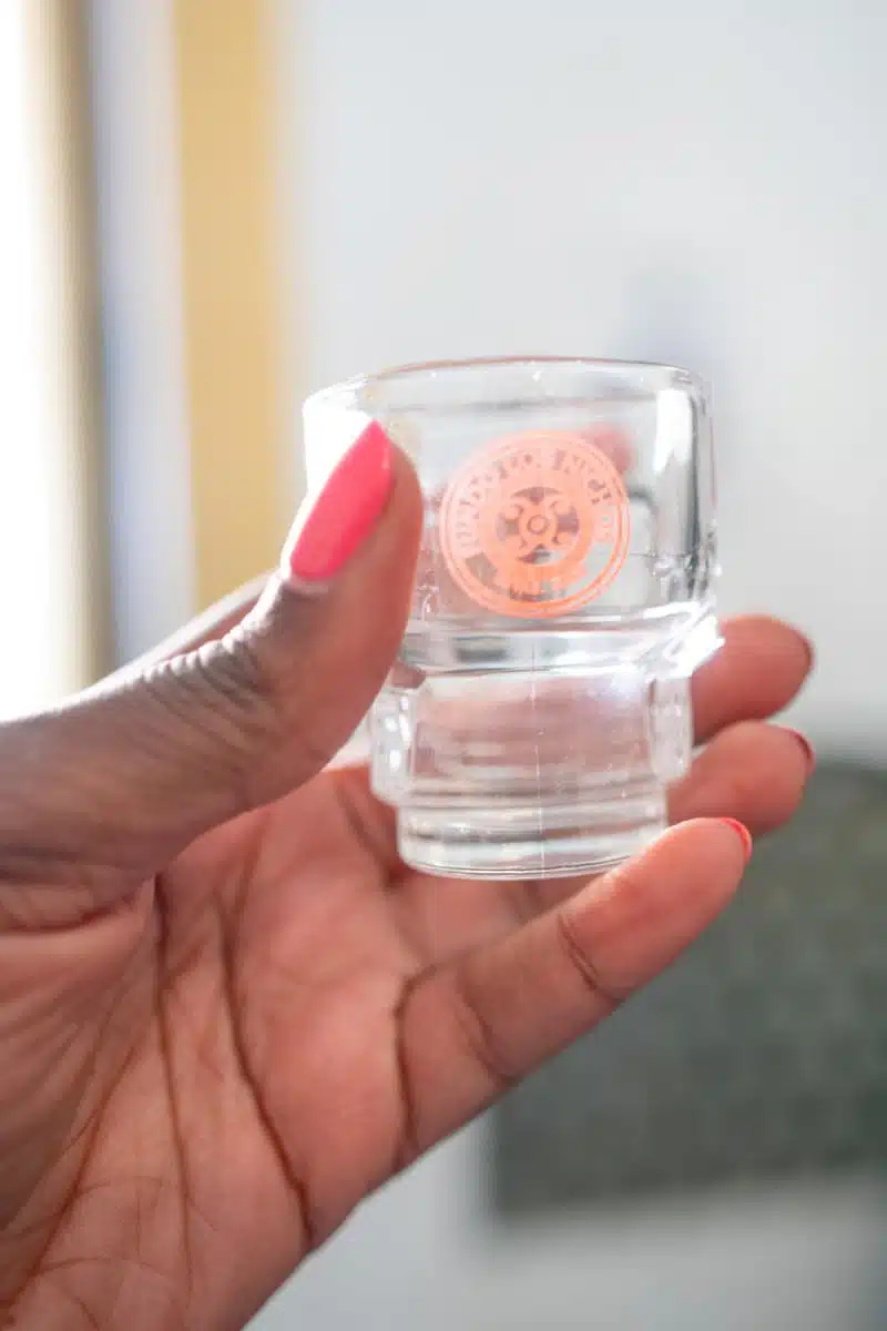 Hand holding a small branded pisco tasting glass at Fundo Los Nichos near Pisco Elqui