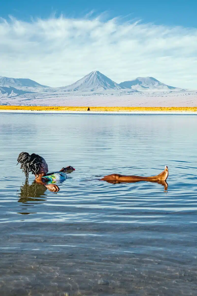 Julianna floating in the clear salty water of Laguna Piedra below Licancabur and a white band of cloud