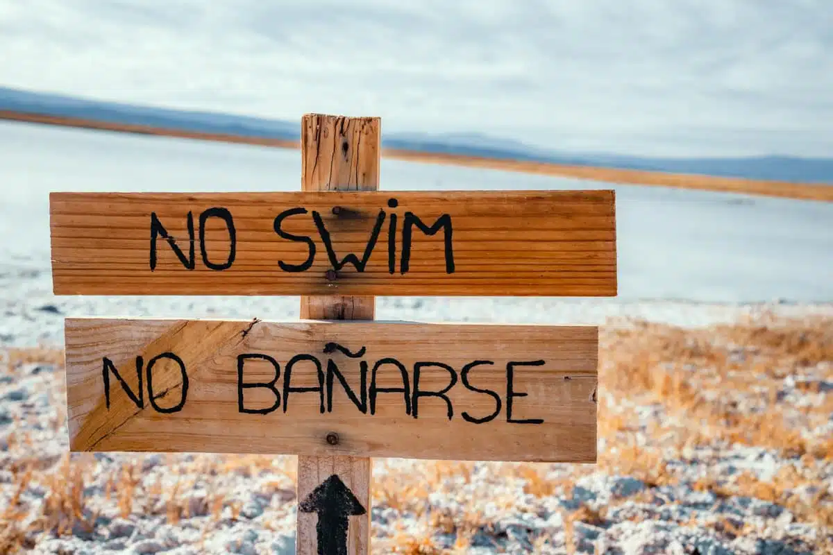 Hand-painted wooden No swim, No bañarse sign on the salt crust beside Laguna Cejar