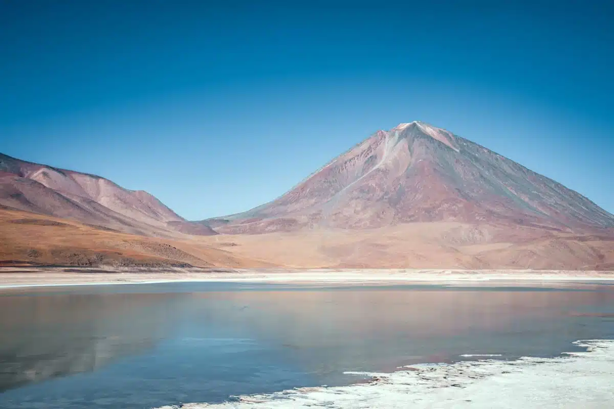 Calm water of Laguna Verde in Bolivia's Eduardo Avaroa reserve with the cone of Licancabur volcano behind