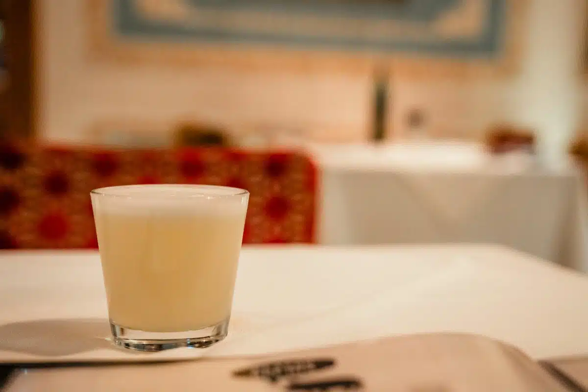 Frothy pisco sour in a short glass on a white tablecloth at Liguria, Santiago