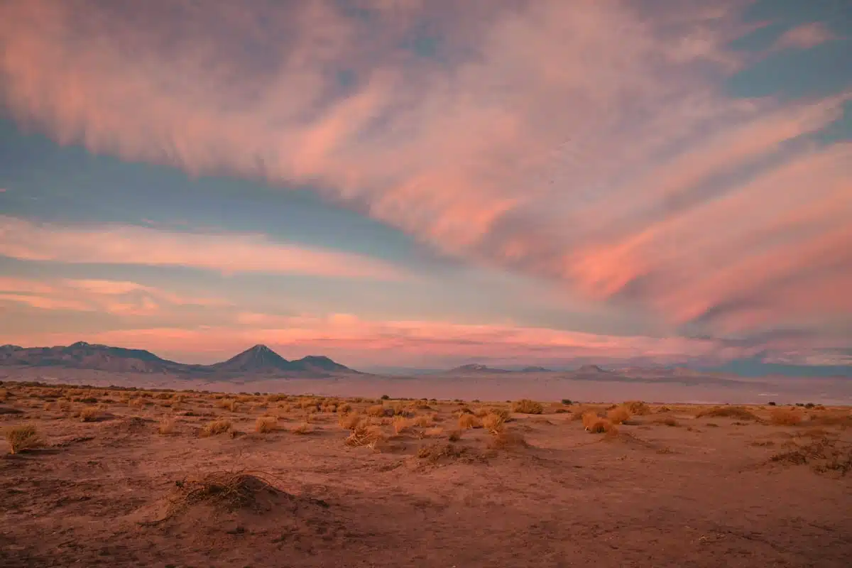 Pink and blue clouds streaking the sky above Licancabur and the red desert after sunset near San Pedro de Atacama