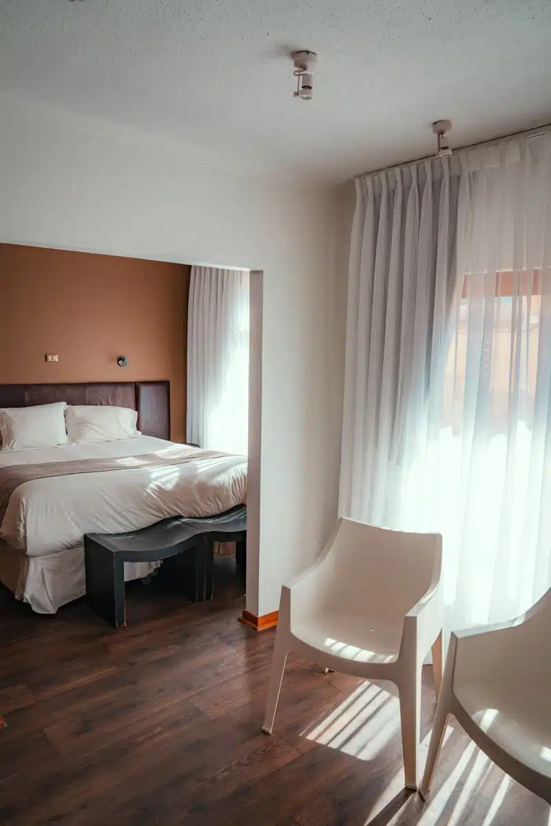 Hotel bedroom with white bed, wooden floor and sheer curtains at Terral Hotel & Spa in Vicuña