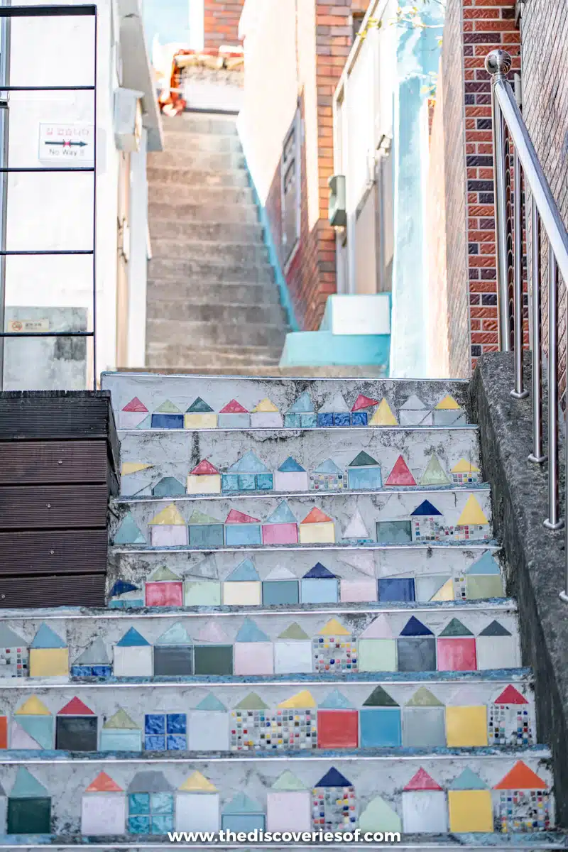 A narrow staircase between houses in Gamcheon Culture Village, Busan, with colourful tiles of little houses set into each step