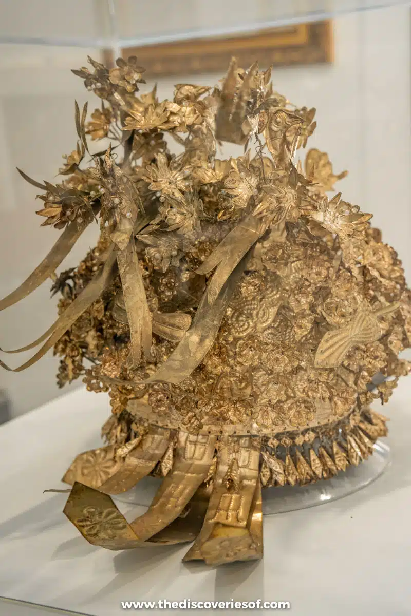 A gilded ceremonial headdress covered in golden leaves and flowers on display at the Gapjaok Hat Gallery in Mokpo