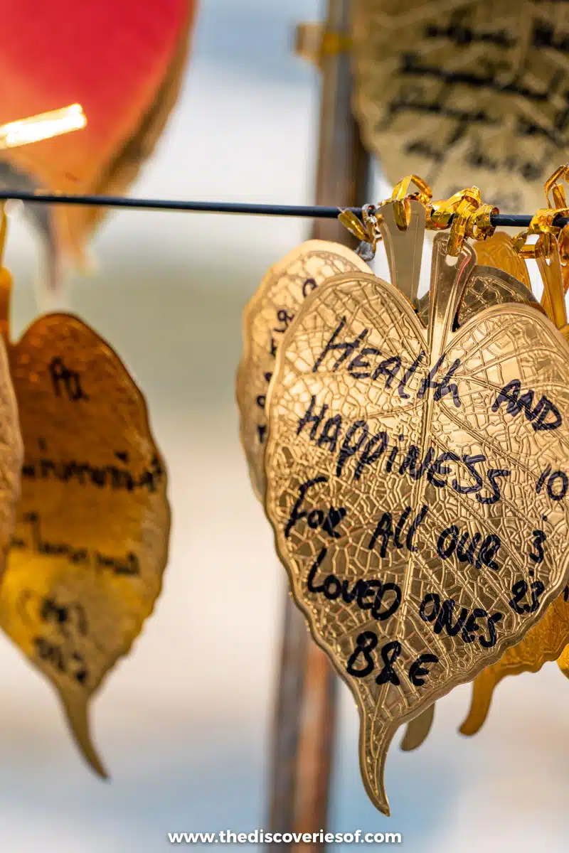 Golden leaf-shaped wish plaques with handwritten messages hanging from a wire at Haedong Yonggungsa temple in Busan