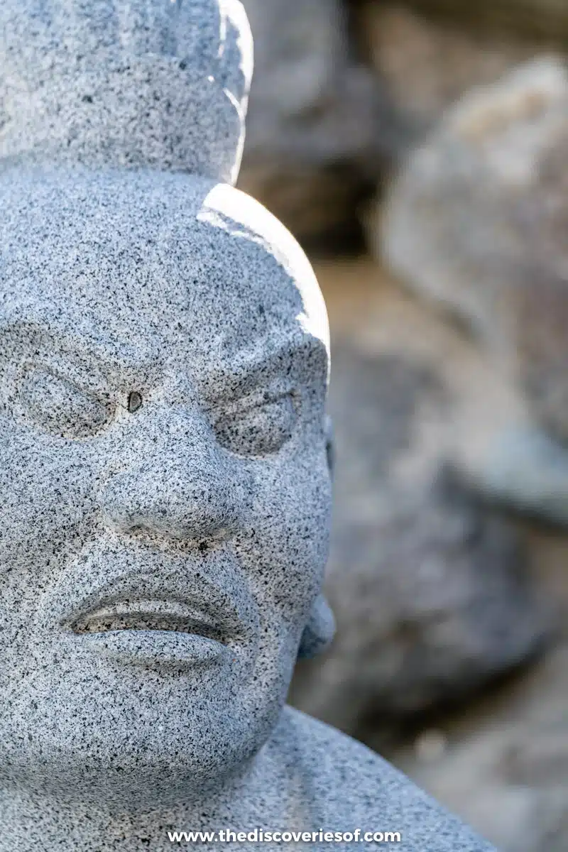Close-up of a frowning carved granite face on one of the stone statues at Haedong Yonggungsa temple, Busan