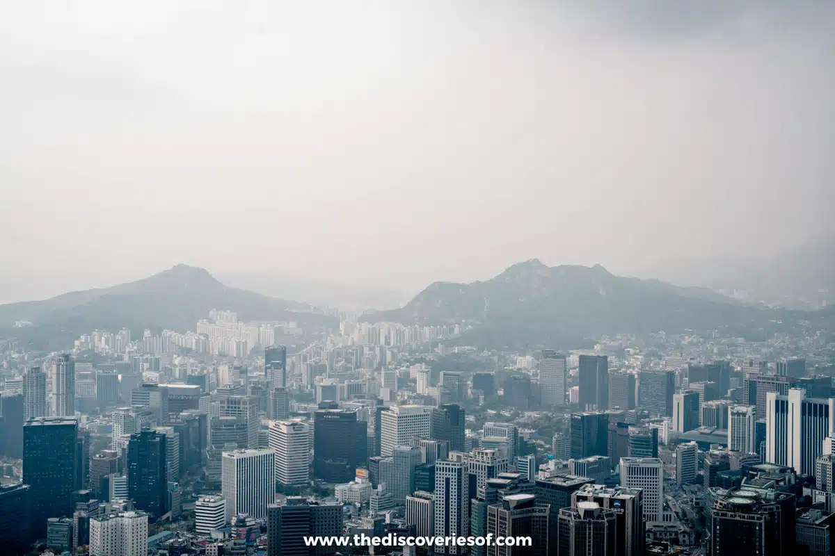 Office towers of downtown Seoul with rocky mountain peaks behind, seen from the N Seoul Tower observation deck