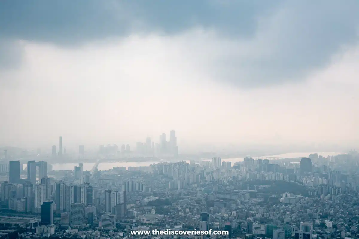 The Han River and distant high-rises through the haze under a grey sky, seen from N Seoul Tower in Seoul