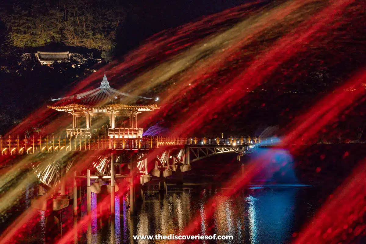 Long-exposure streaks of red light across the water in front of the illuminated Woryeonggyo Bridge, Andong