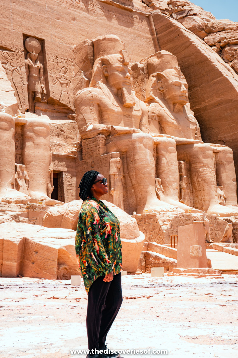 Julianna in a long-sleeved green patterned shirt and black trousers in front of the colossi at Abu Simbel
