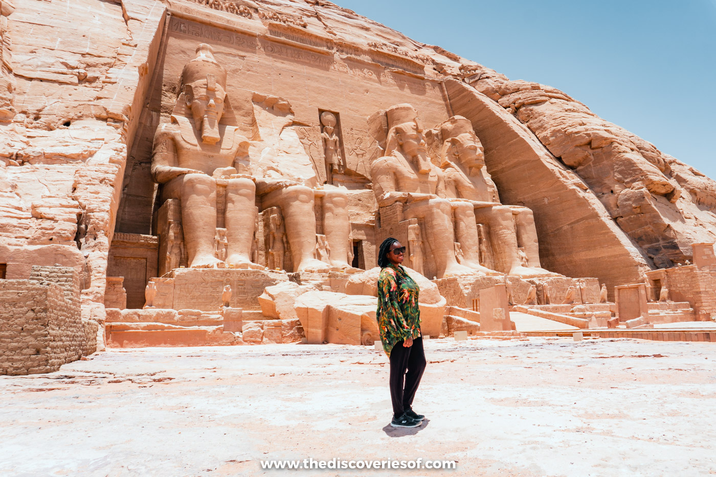 Julianna standing in the forecourt below the four colossal statues of Ramses II at the Great Temple of Abu Simbel