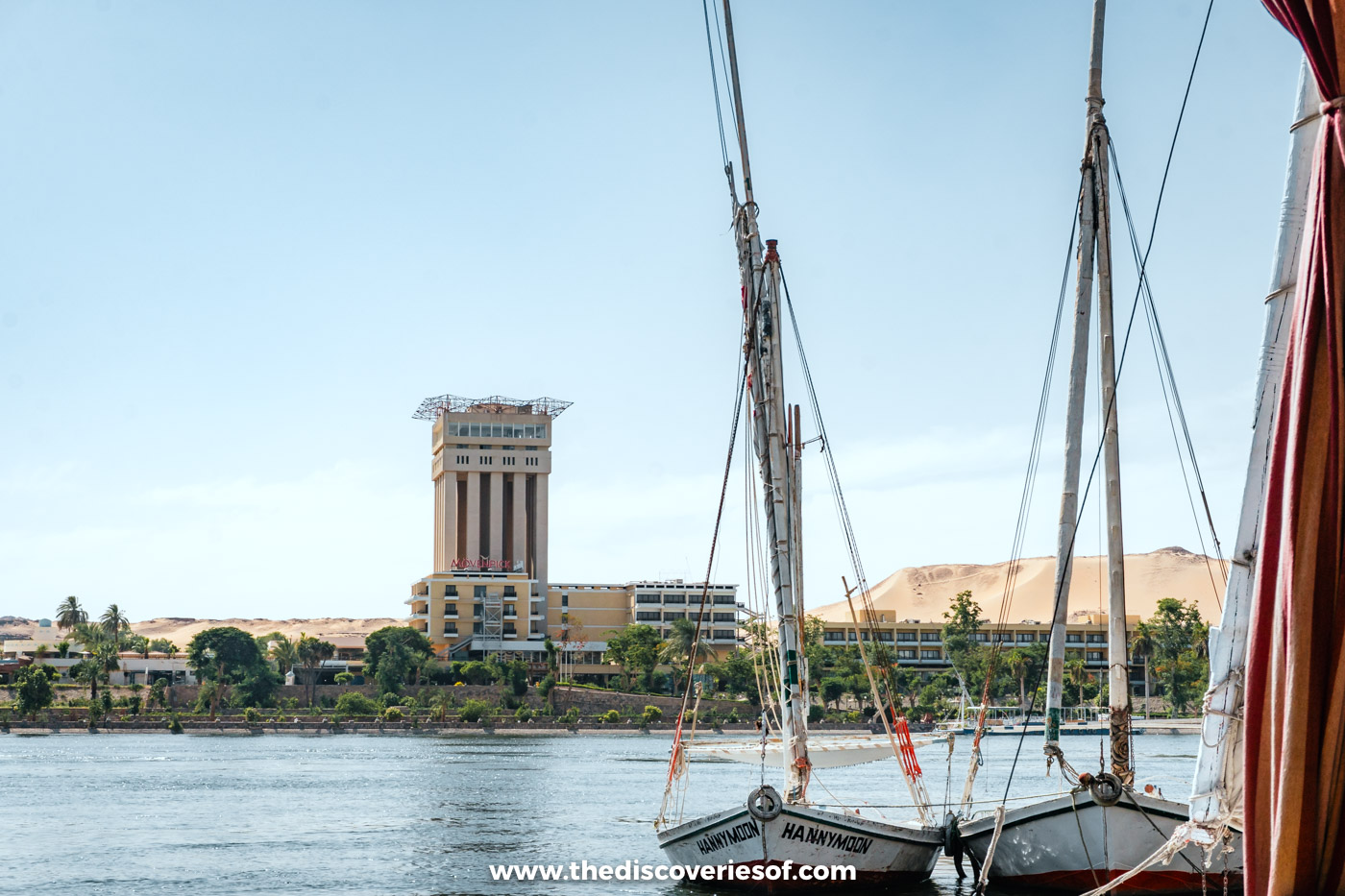 Feluccas moored on the Nile in Aswan with the hotel tower on Elephantine Island behind them