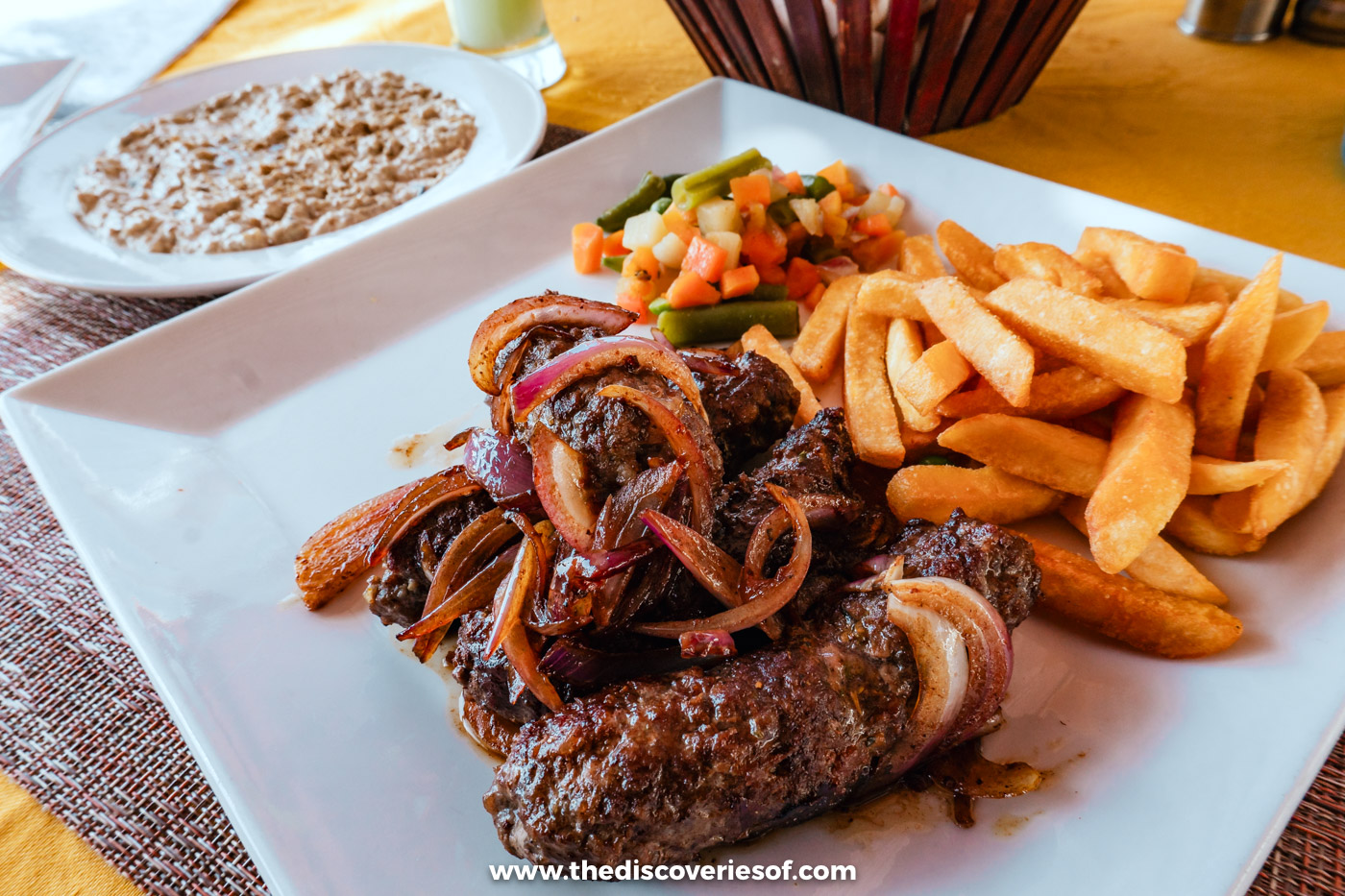 A plate of kofta with fried onions and chips on a table at Salahaddin restaurant on the Aswan Corniche