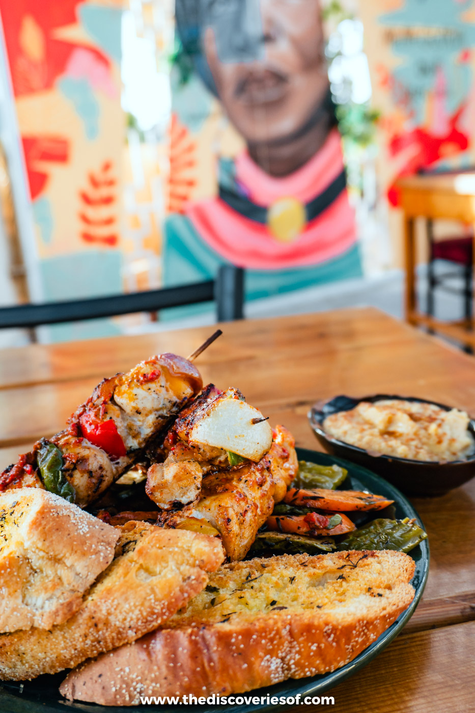 Grilled skewers with toasted bread and a dip on a wooden table at Makani restaurant in Aswan