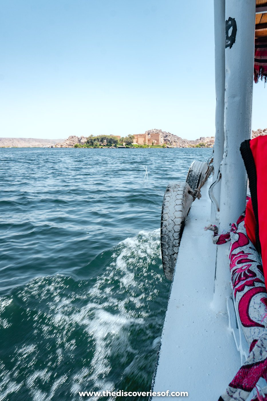 View from a motorboat on the water towards Agilkia Island and Philae Temple near Aswan under a blue sky