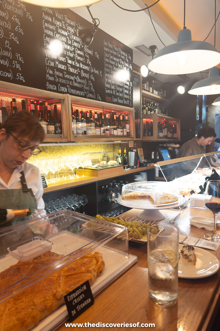 A chalkboard wine list above the bar and a tortilla on the counter at Cork wine bar, Bilbao