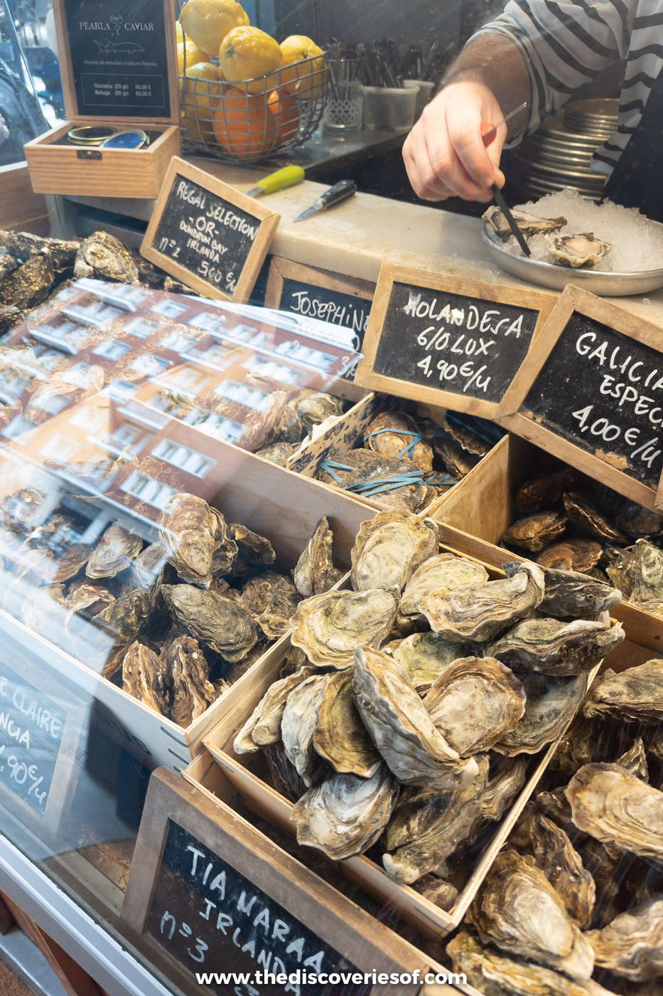 Oysters in wooden crates under chalkboard signs naming each variety at the El Puertito counter, Bilbao