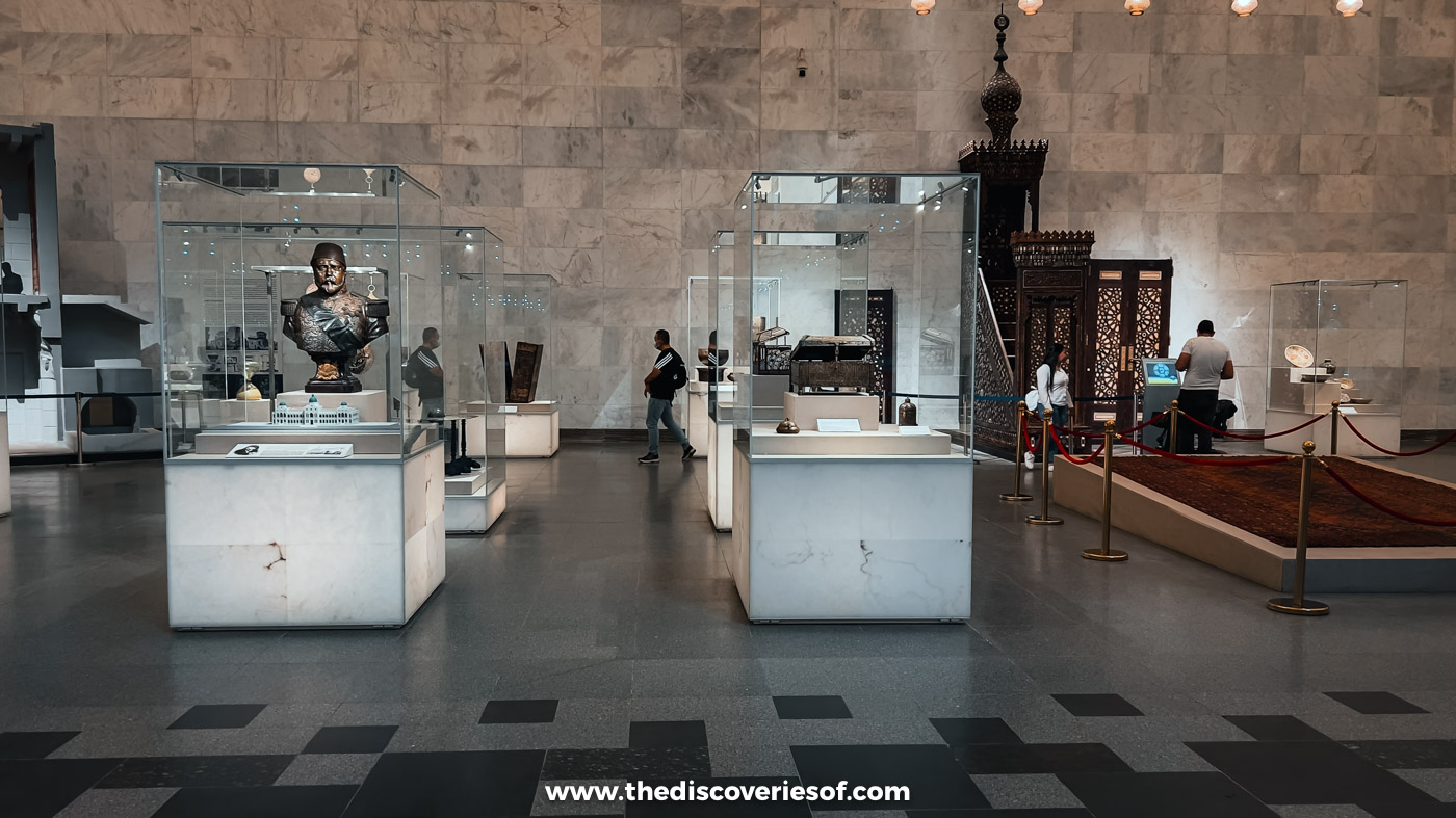 Glass showcases and statues in a stone-walled gallery at the National Museum of Egyptian Civilisation in Cairo