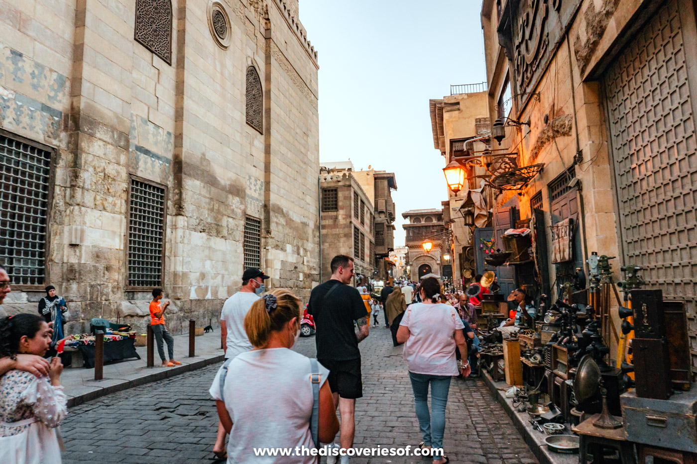 Visitors walking along the cobbled Al-Muizz Street in Islamic Cairo past old stone facades and shops