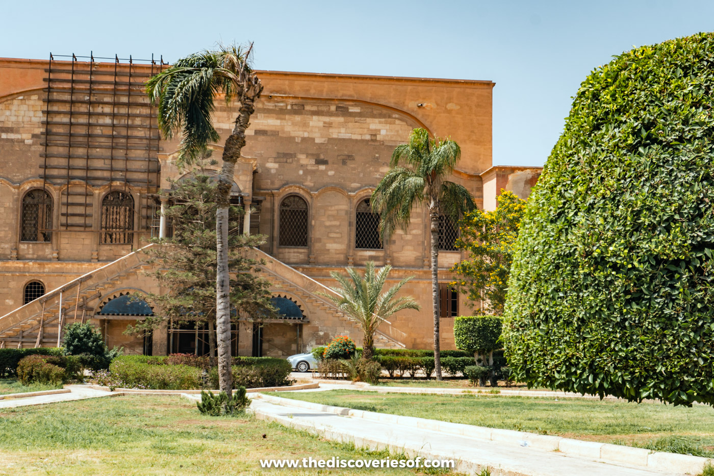 Palm trees, lawns and a historic building in the gardens inside the walls of the Cairo Citadel