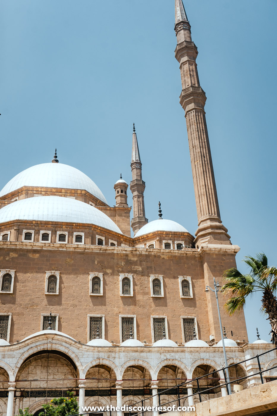 Grey domes and a tall pencil minaret of the Mosque of Muhammad Ali against a blue sky in Cairo