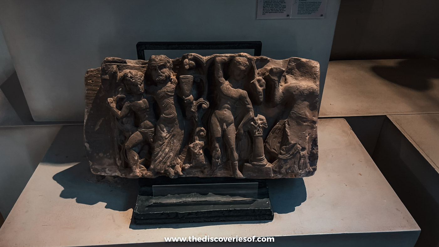 A carved stone relief crowded with human figures, displayed in a case in the Coptic Museum in Cairo
