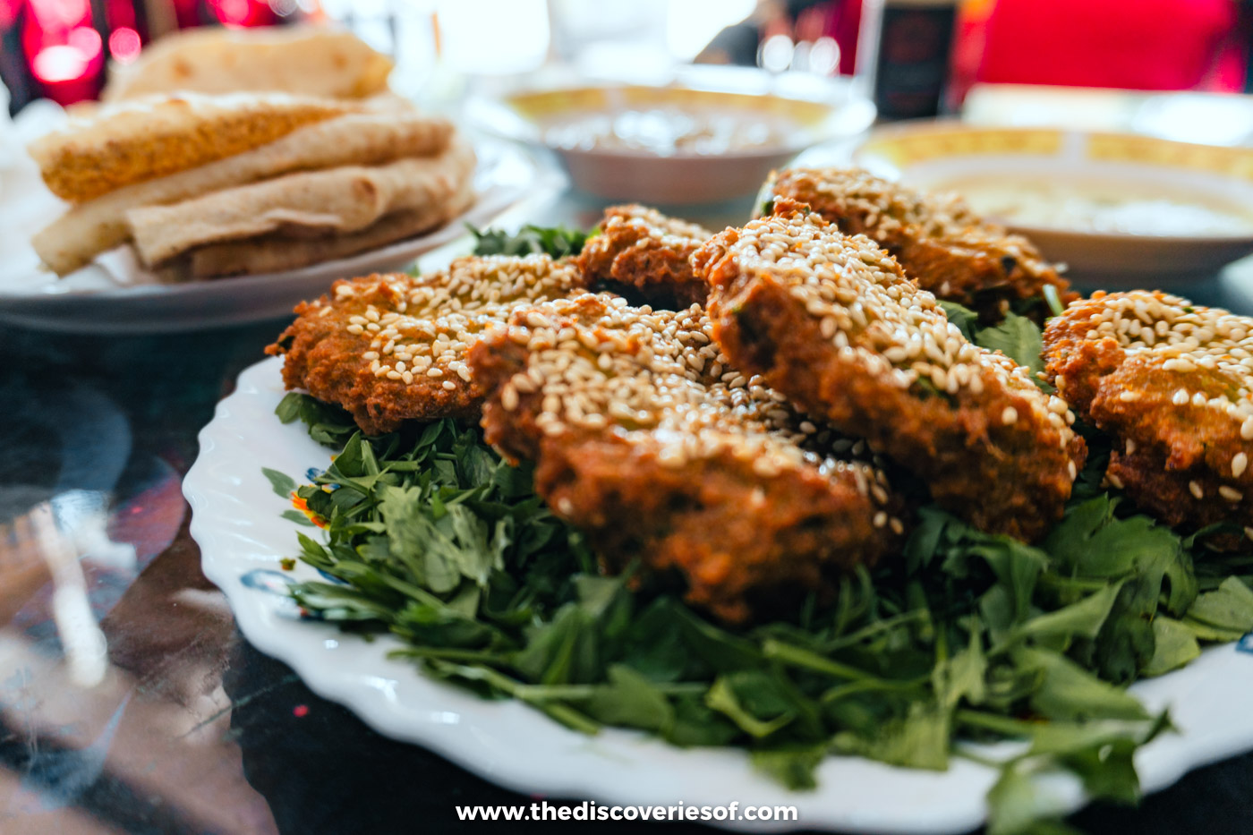 A plate of crisp sesame-topped falafel on greens with bread and dips at a lunch in Coptic Cairo