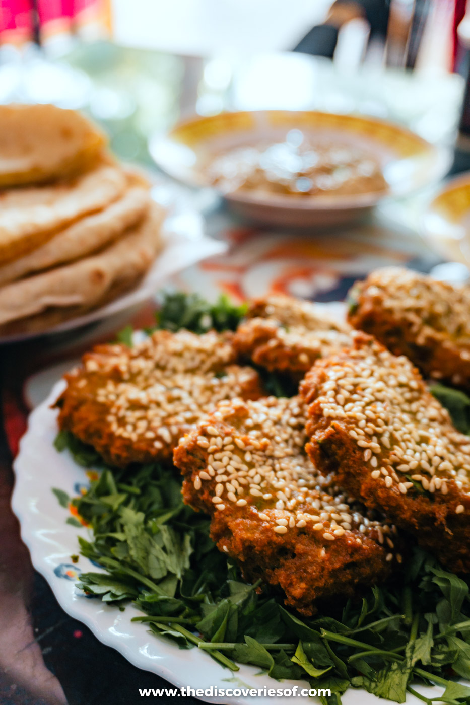 A plate of sesame-crusted Egyptian falafel on salad leaves with bread and dips at a lunch in Cairo
