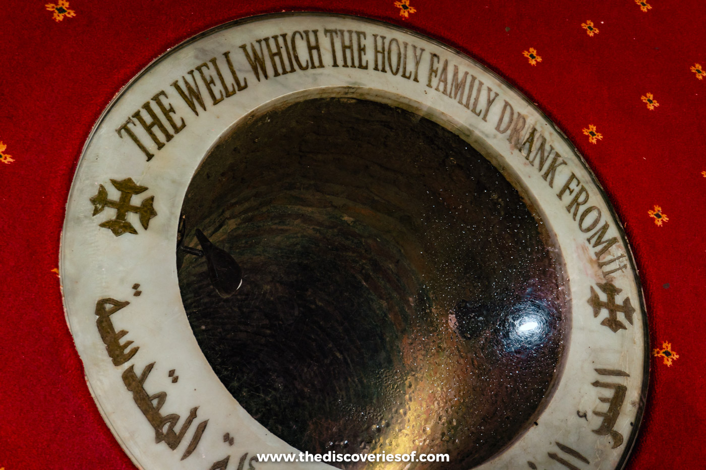 A round well set into a red carpeted floor, inscribed as the well the Holy Family drank from