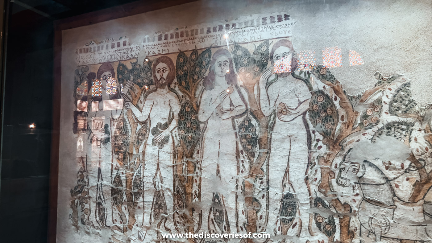 A faded medieval wall painting of Adam and Eve and other figures in the Coptic Museum in Cairo