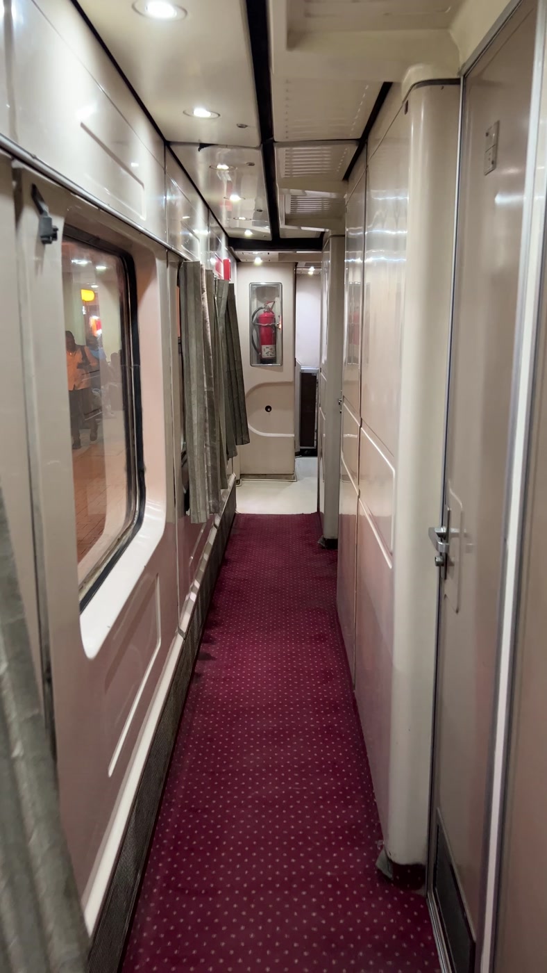 The narrow carpeted corridor of a sleeping car on the Egyptian sleeper train, with cabin doors along one side