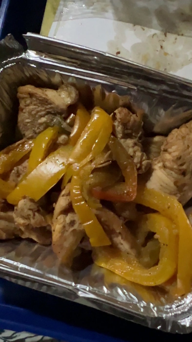 A foil tray of chicken and yellow peppers served for dinner in a cabin on the Egyptian sleeper train
