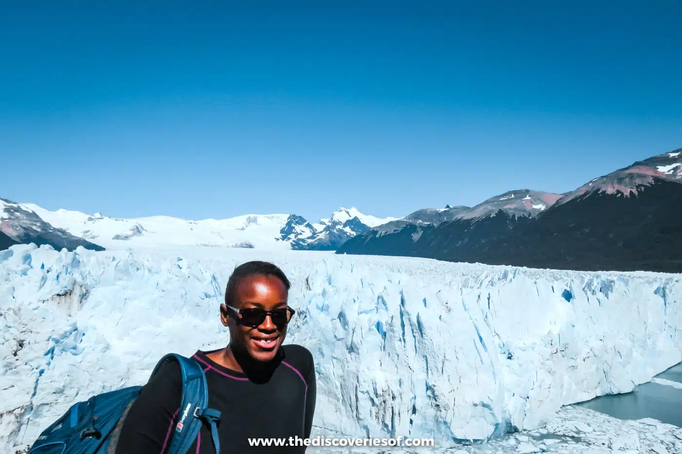 Julianna Barnaby smiling in sunglasses in front of the Perito Moreno Glacier, Argentina