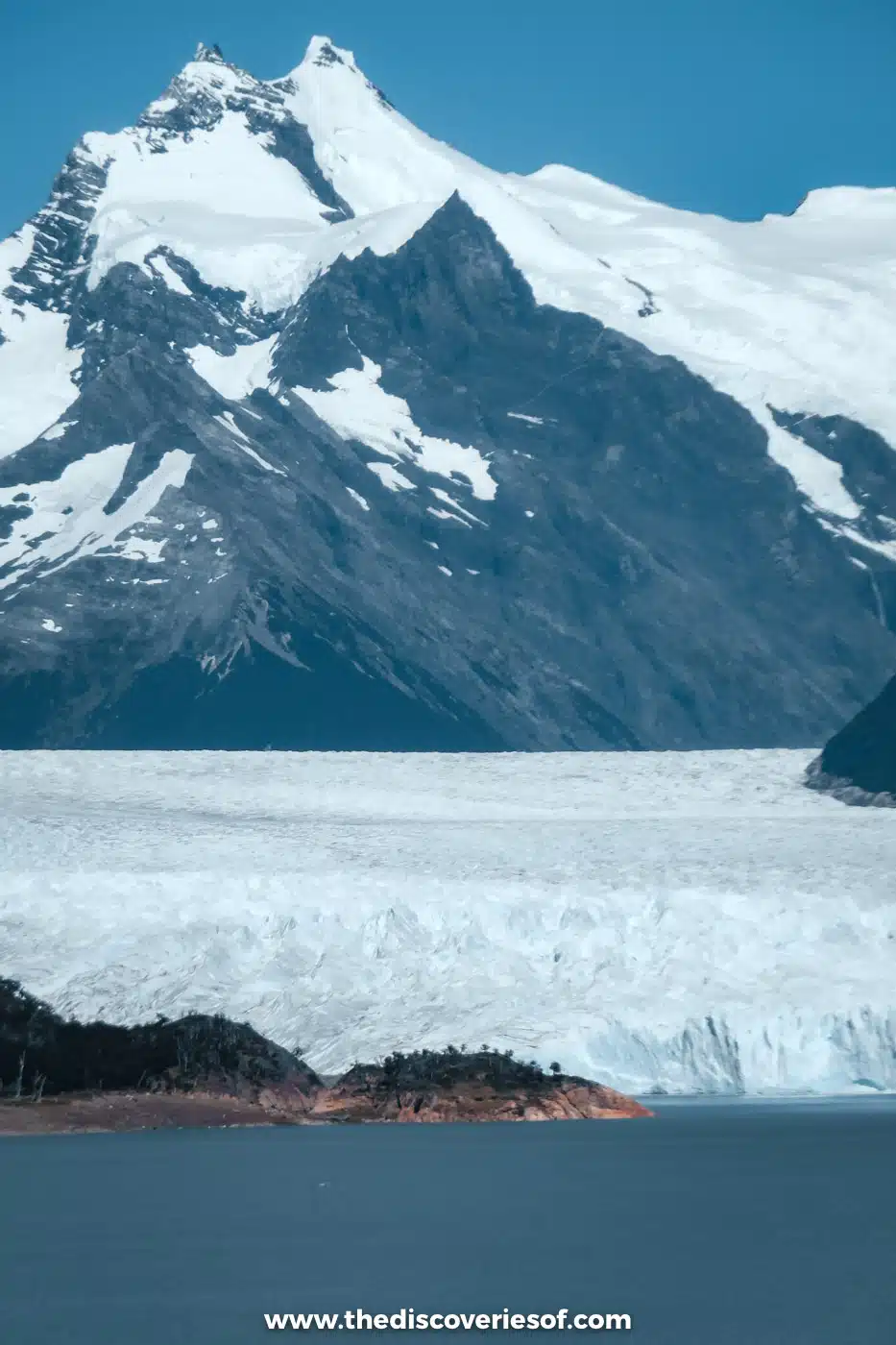 Perito Moreno Glacier flowing between snowy mountains into blue Lago Argentino, Argentina