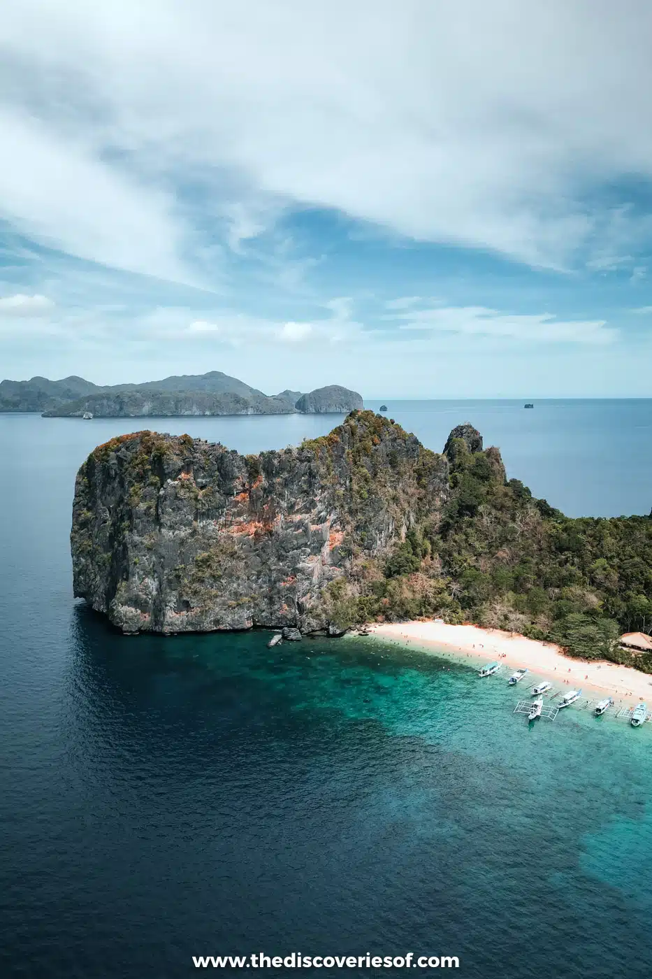 Aerial view of a limestone outcrop and white beach at Helicopter Island with boats offshore, El Nido