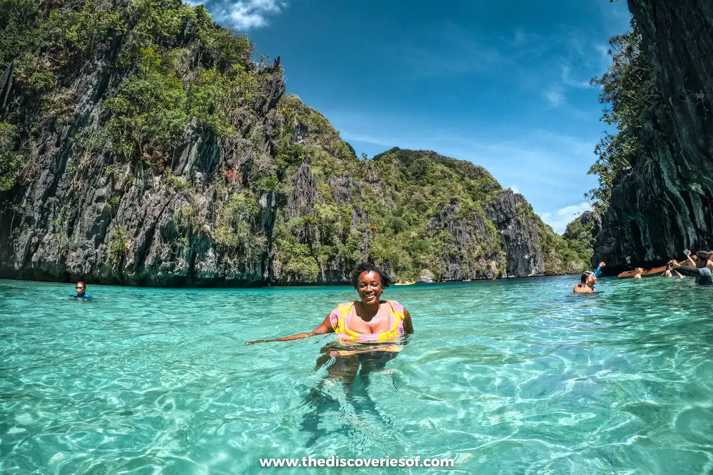 Julianna swimming in the turquoise Big Lagoon below green limestone cliffs, El Nido