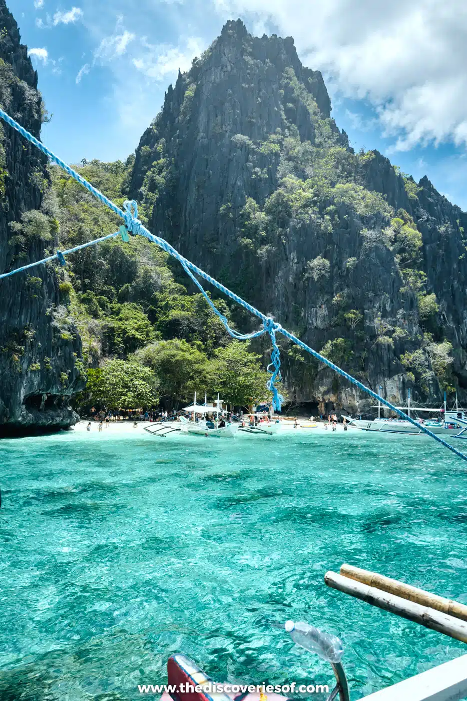 View from the bow of a bangka towards towering limestone cliffs and turquoise water on El Nido Tour A