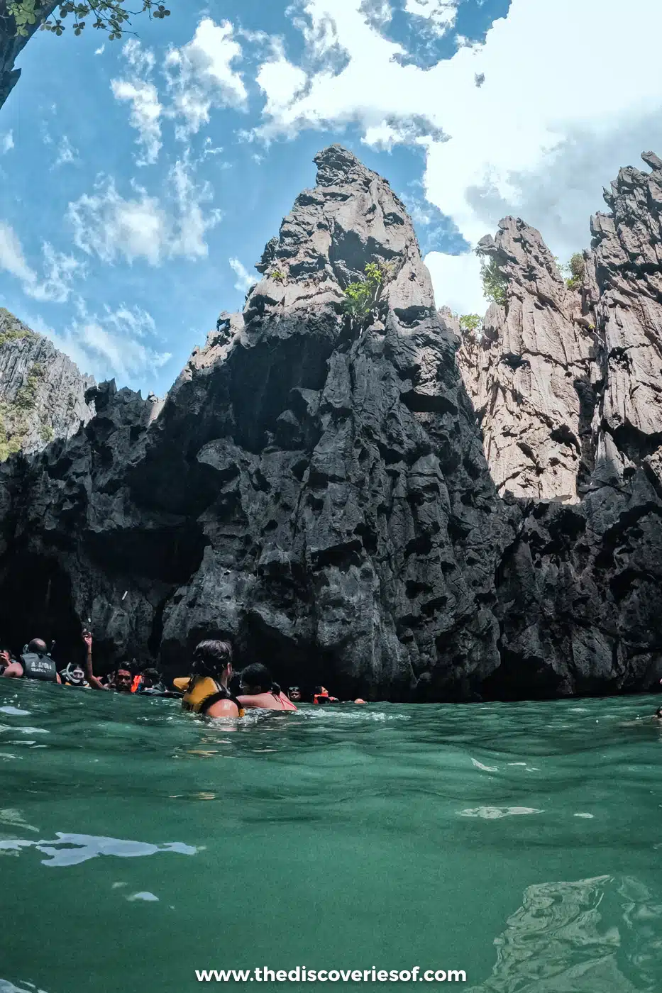Swimmers in life jackets below jagged limestone pinnacles near the Secret Lagoon, El Nido