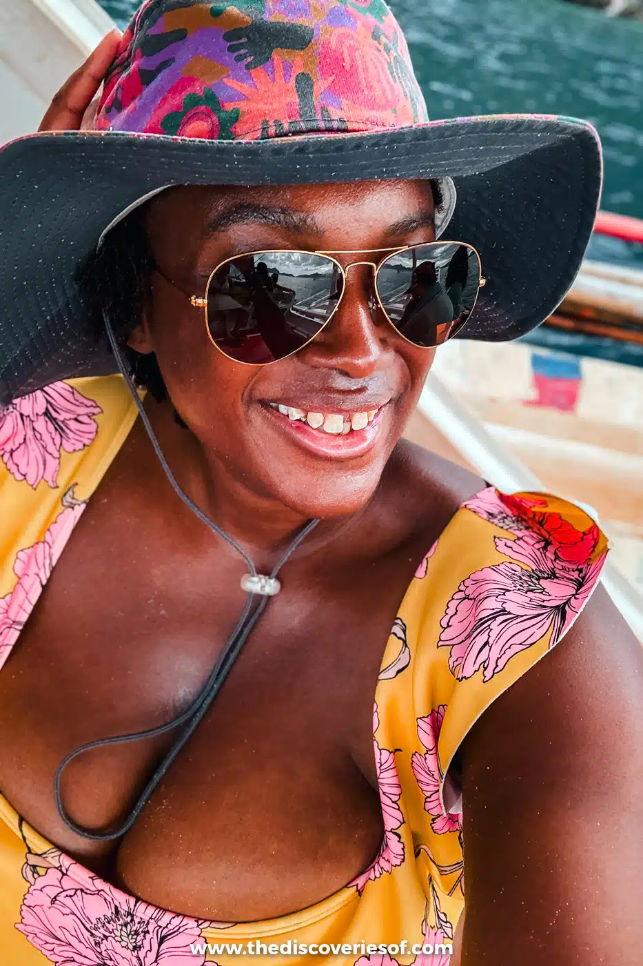 Julianna in a pink sun hat and sunglasses smiling on an island-hopping boat in El Nido