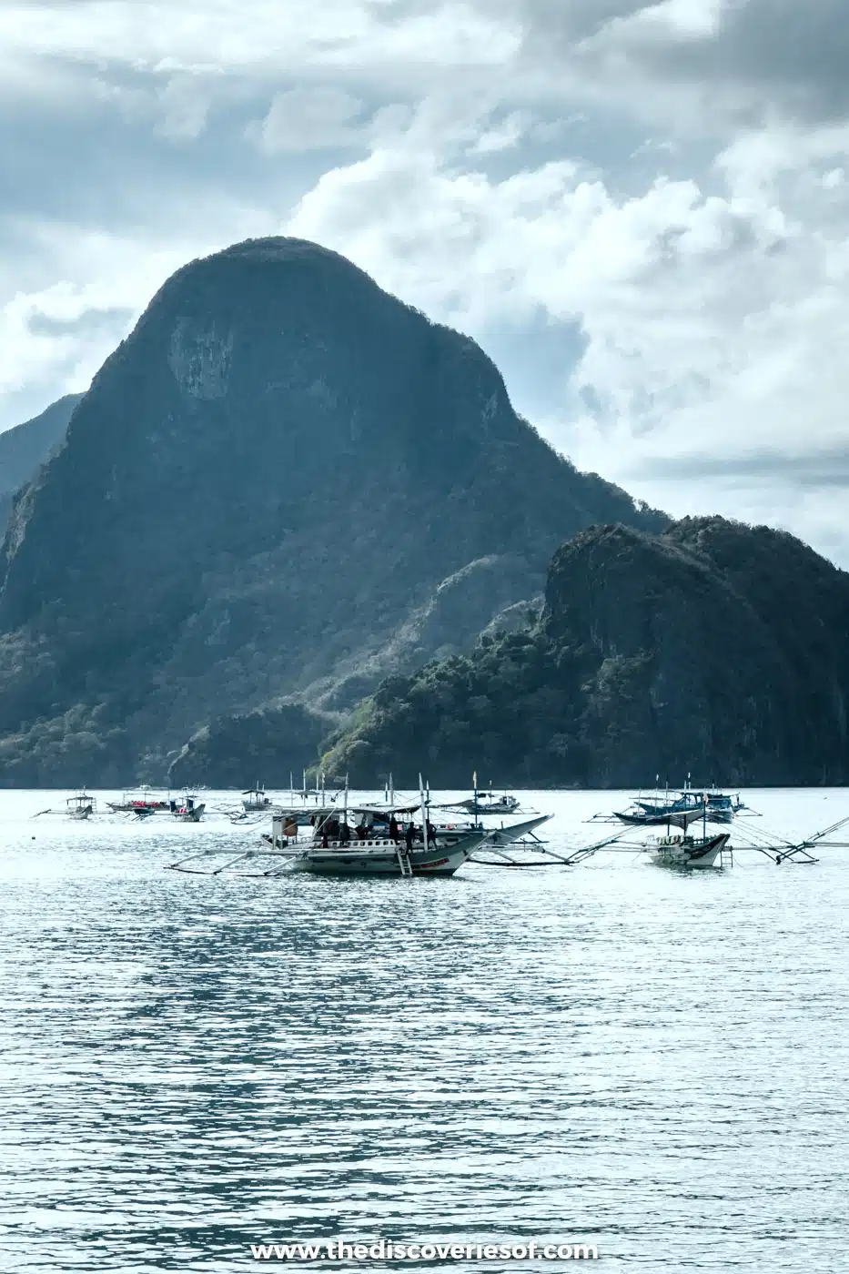 Bangka boats moored in the bay below the steep green peak of Cadlao Island, El Nido